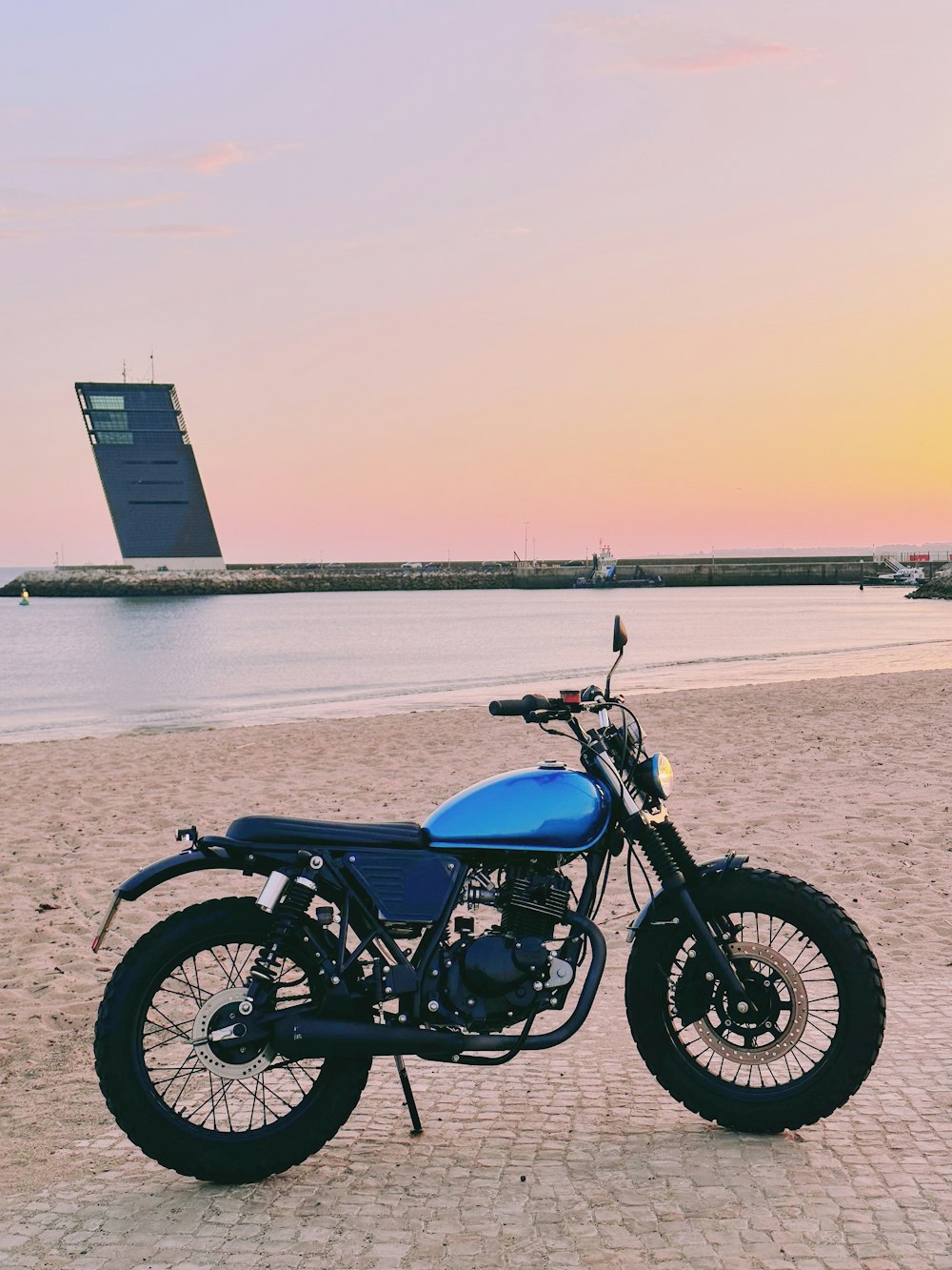 a motorcycle parked on a beach next to the ocean