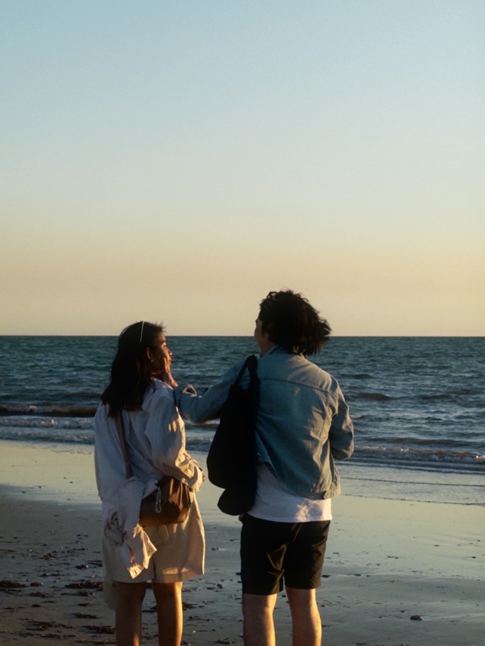 a couple of people standing on top of a beach