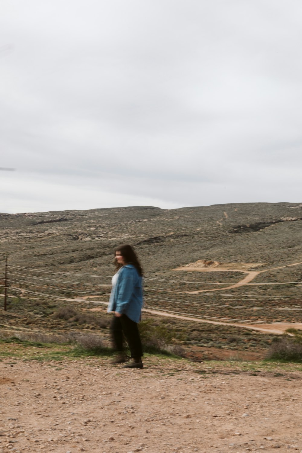 a woman standing in the middle of a dirt road