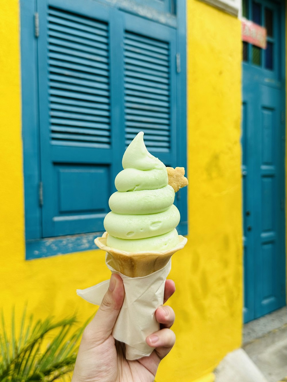 a person holding up a green ice cream cone