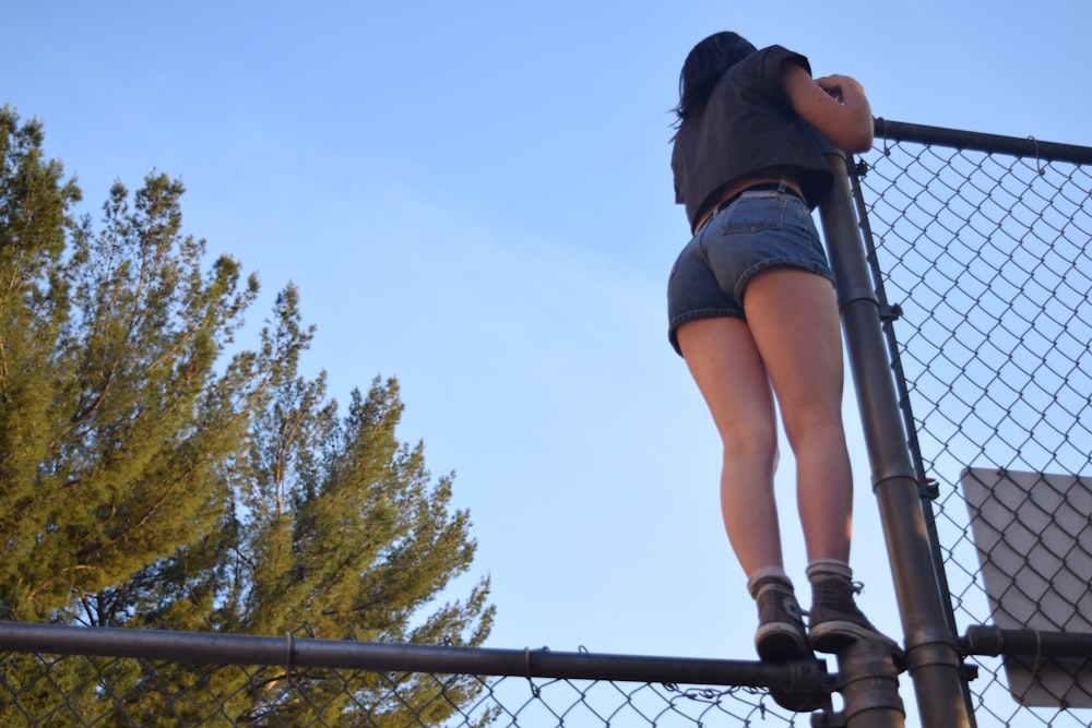 a woman standing on a fence with her back to the camera