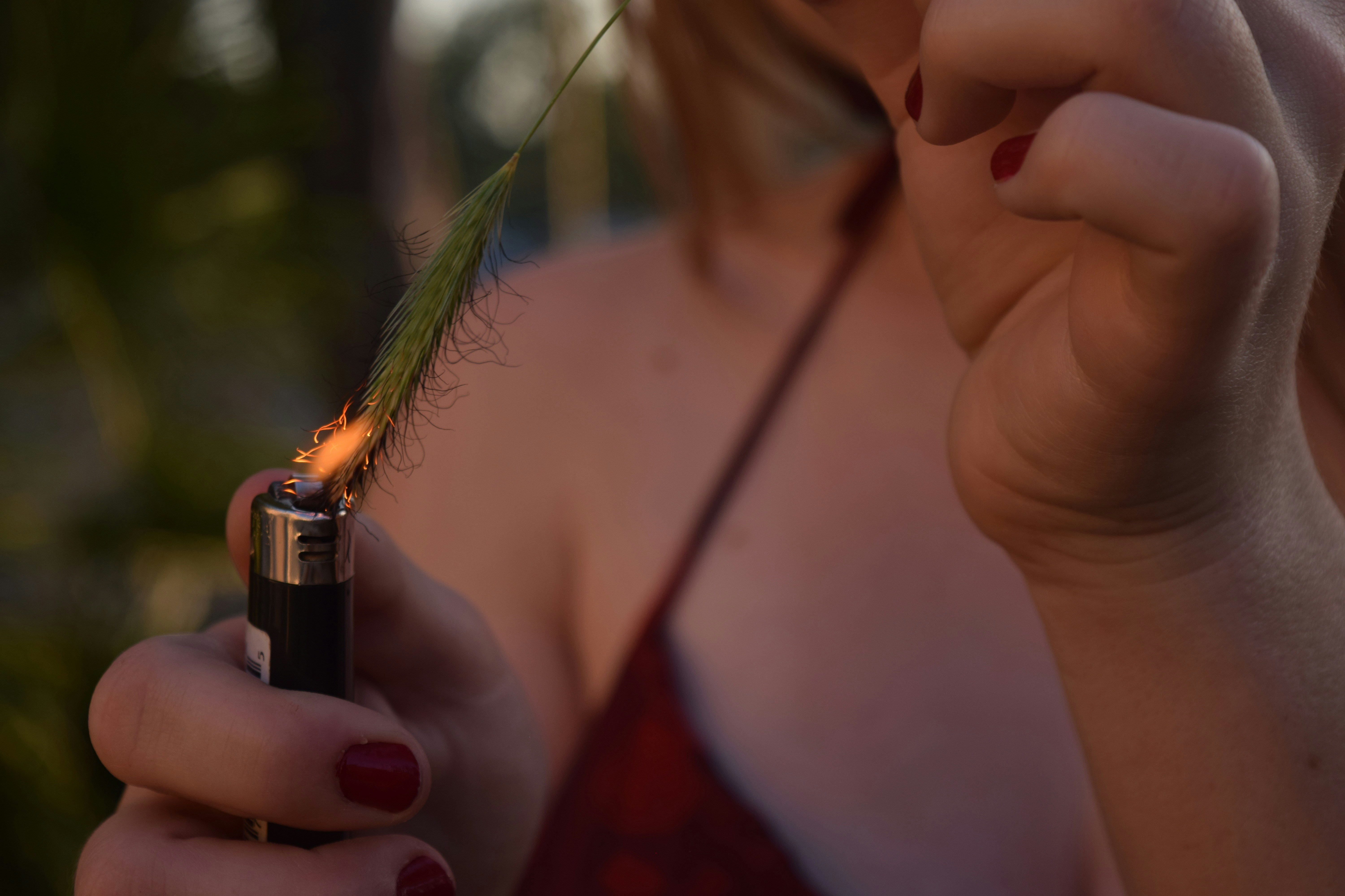 a woman holding a lighter with a feather on it