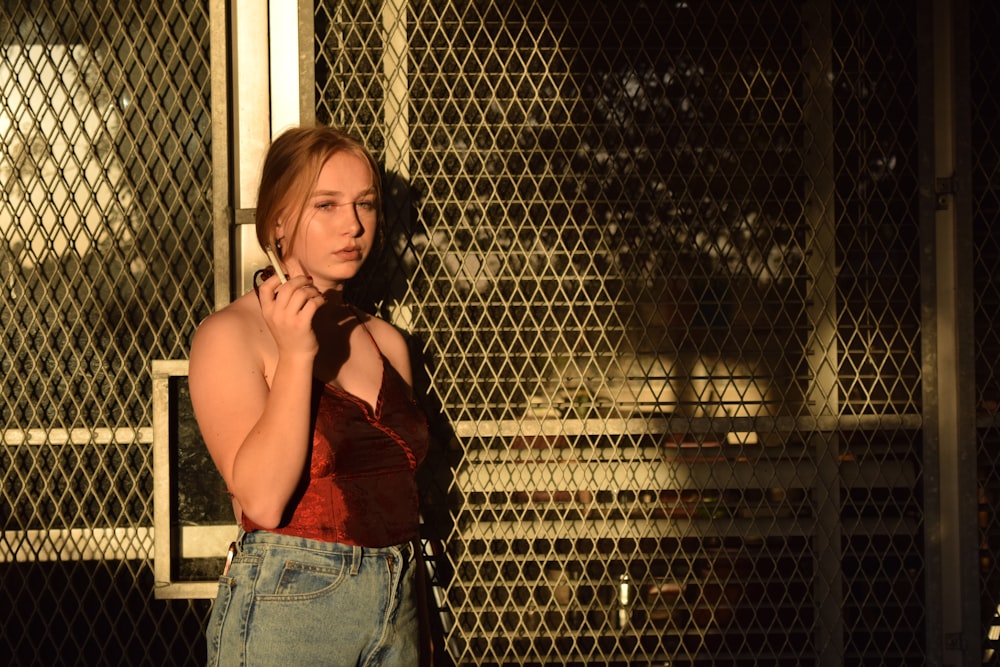 a woman standing in front of a metal fence