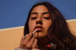 a woman smoking a cigarette with a blue sky in the background