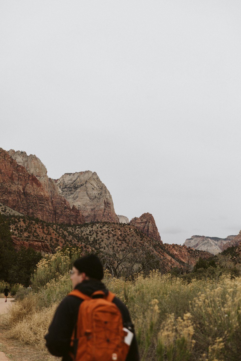 a man with a backpack walking down a dirt road