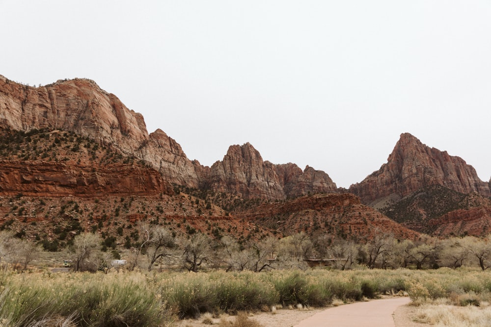 a dirt road in front of a mountain range