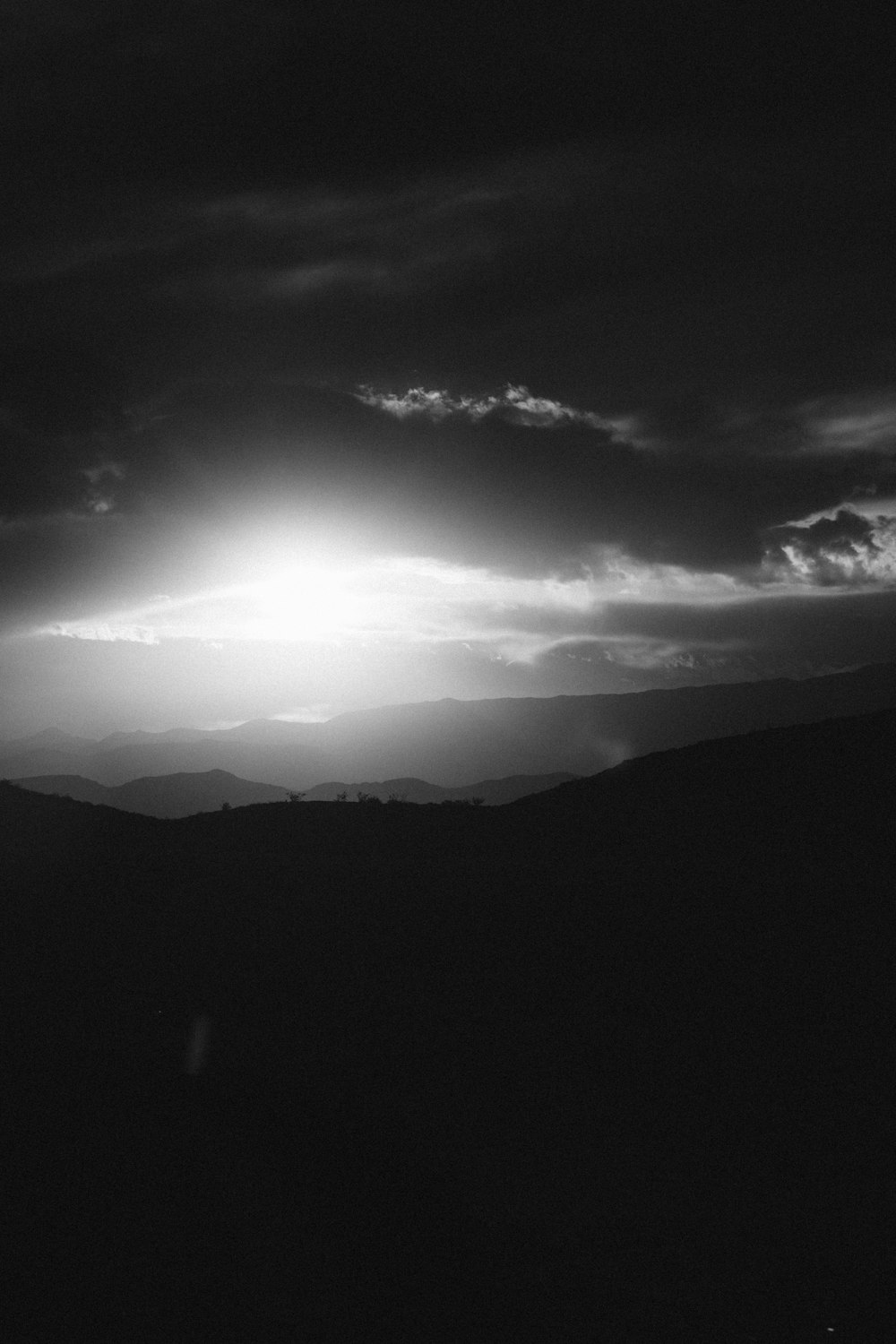 a black and white photo of the sun shining through the clouds