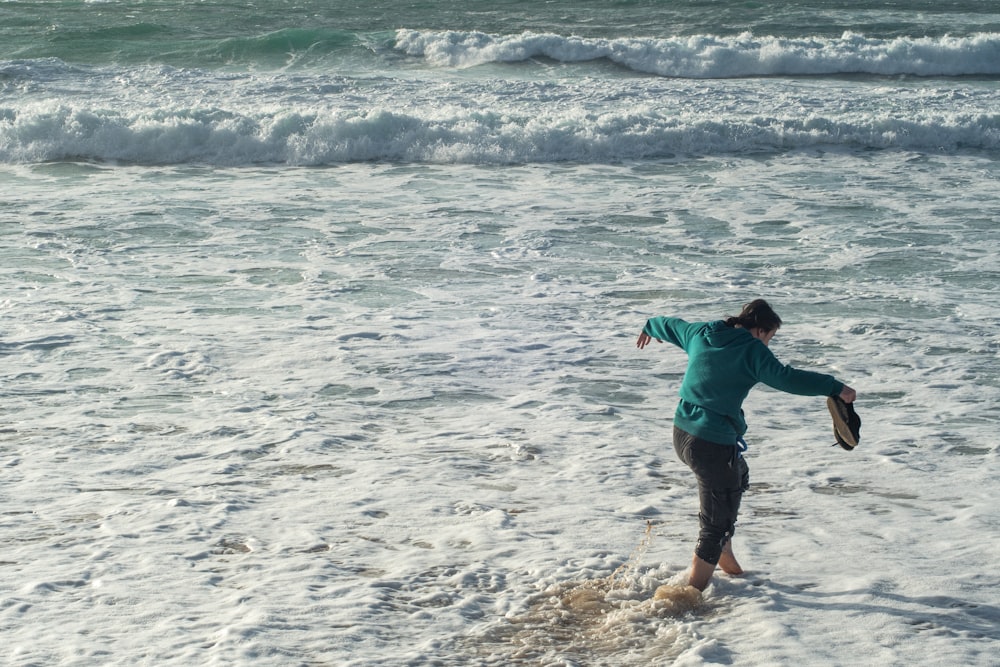 a woman standing in the ocean holding a frisbee