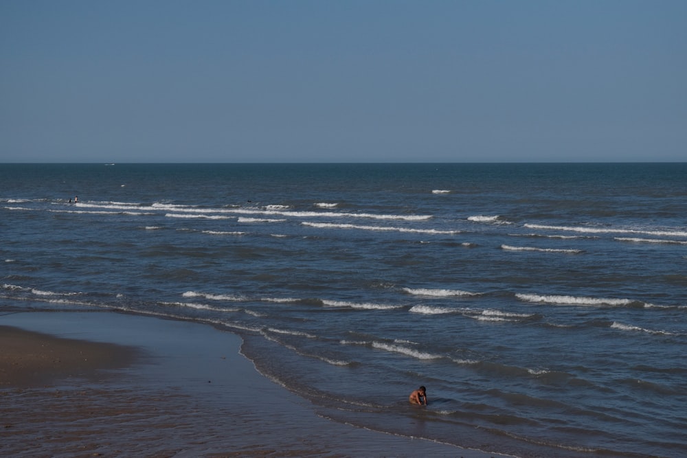 una persona vadeando en el agua en la playa