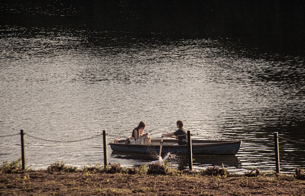 two people in a small boat on a lake