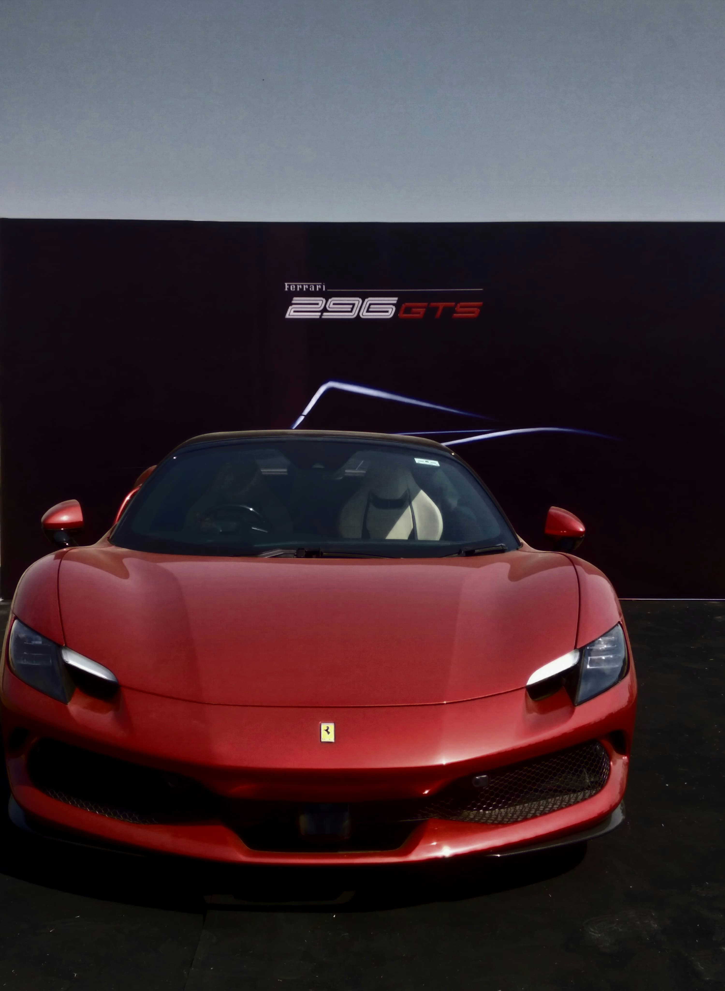 Ferrari 296 GTB in Rosso Corsa red, dramatic studio lighting, pure black background, low-angle shot showing aggressive front splitter