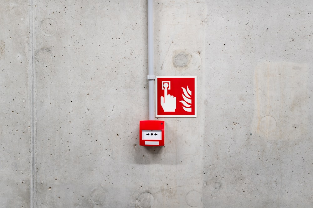 a red and white sign on a concrete wall