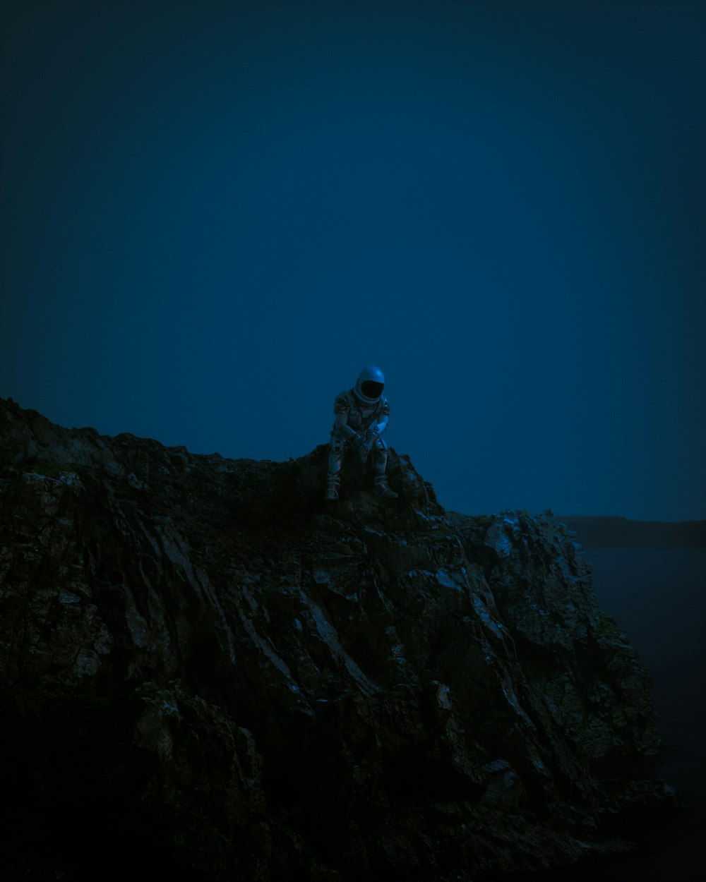 a man sitting on top of a mountain under a blue sky