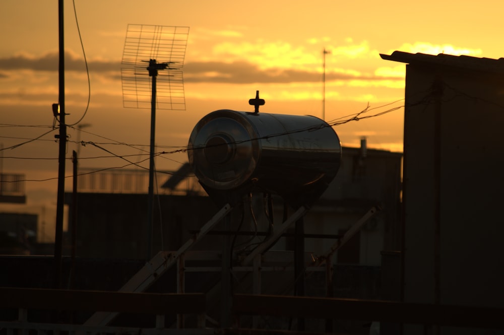 the sun is setting behind a building with a pipe