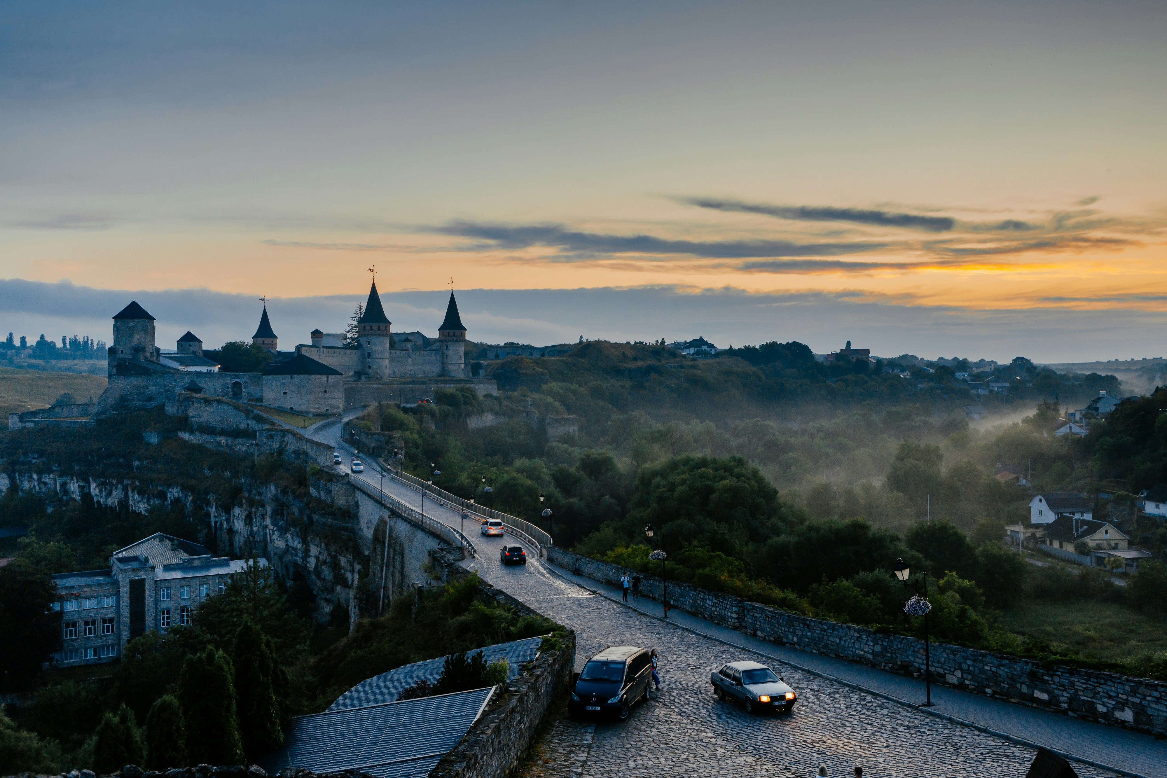Un grupo de coches circulando por una carretera junto a un castillo