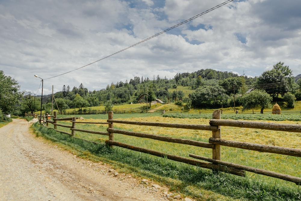a dirt road with a wooden fence on the side of it