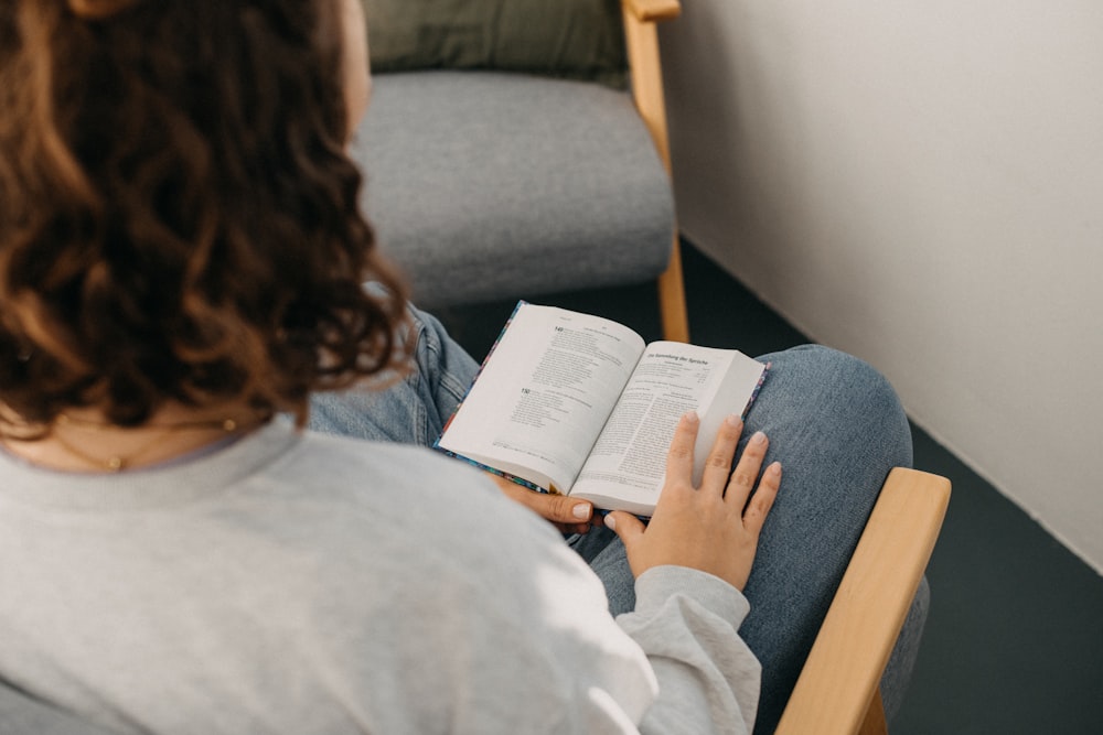 a woman sitting on a chair reading a book