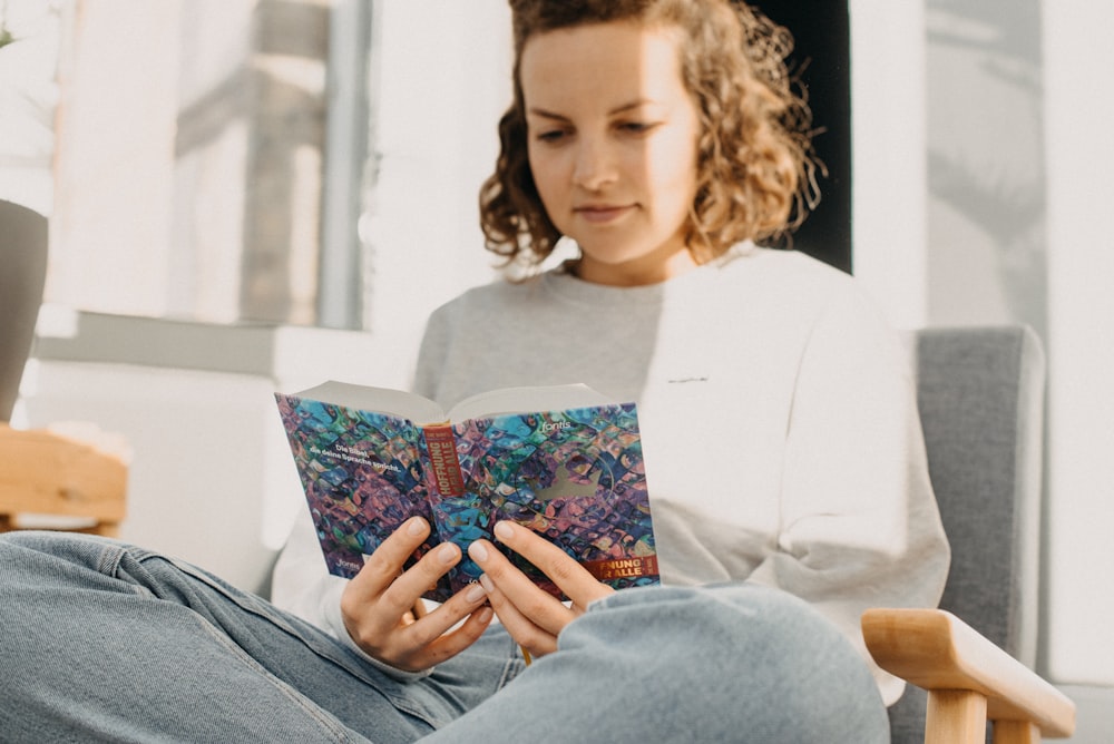 a woman sitting in a chair reading a book