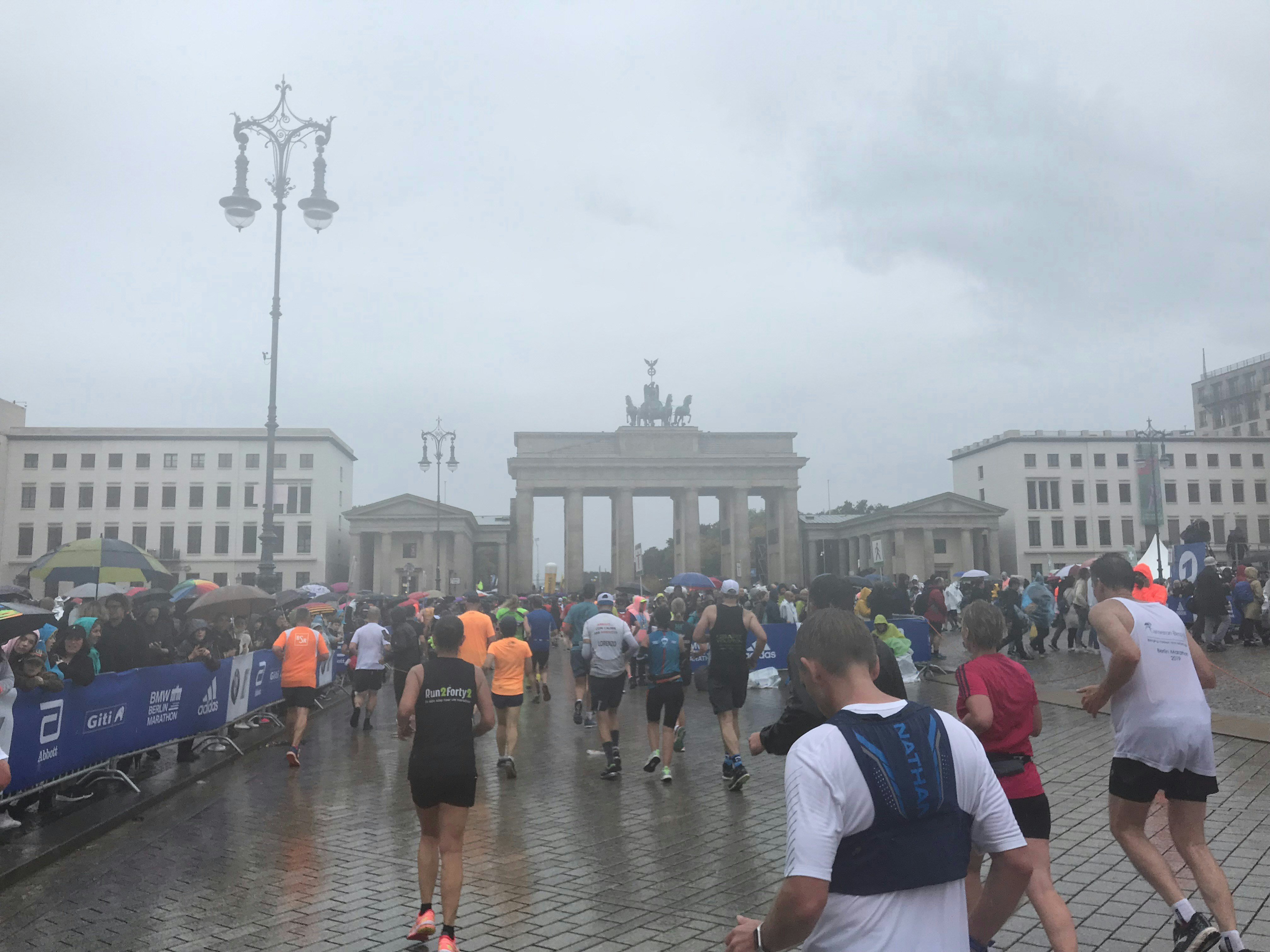 Marathon runners passing through Brandenburg Gate in Berlin with crowds lining the street
