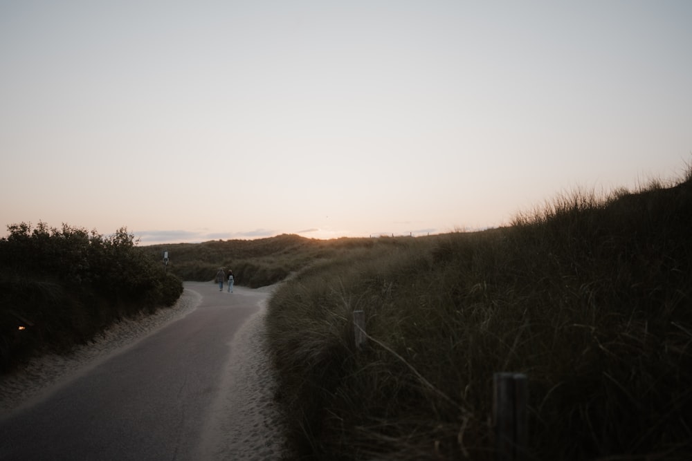 a couple of people walking down a dirt road