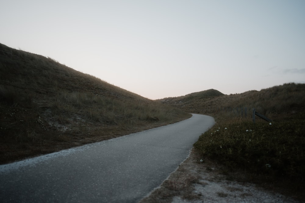 a winding road in the middle of a grassy hill