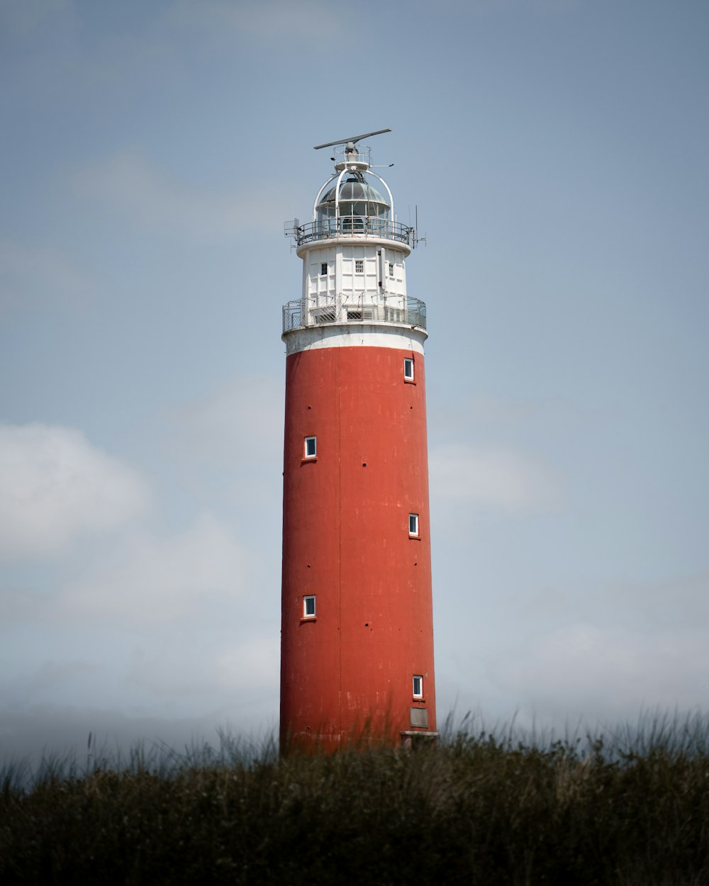 a red and white lighthouse on top of a hill