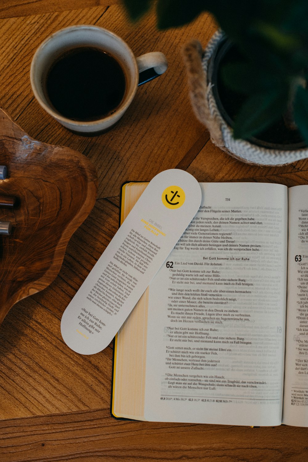 an open book sitting on top of a wooden table next to a cup of coffee