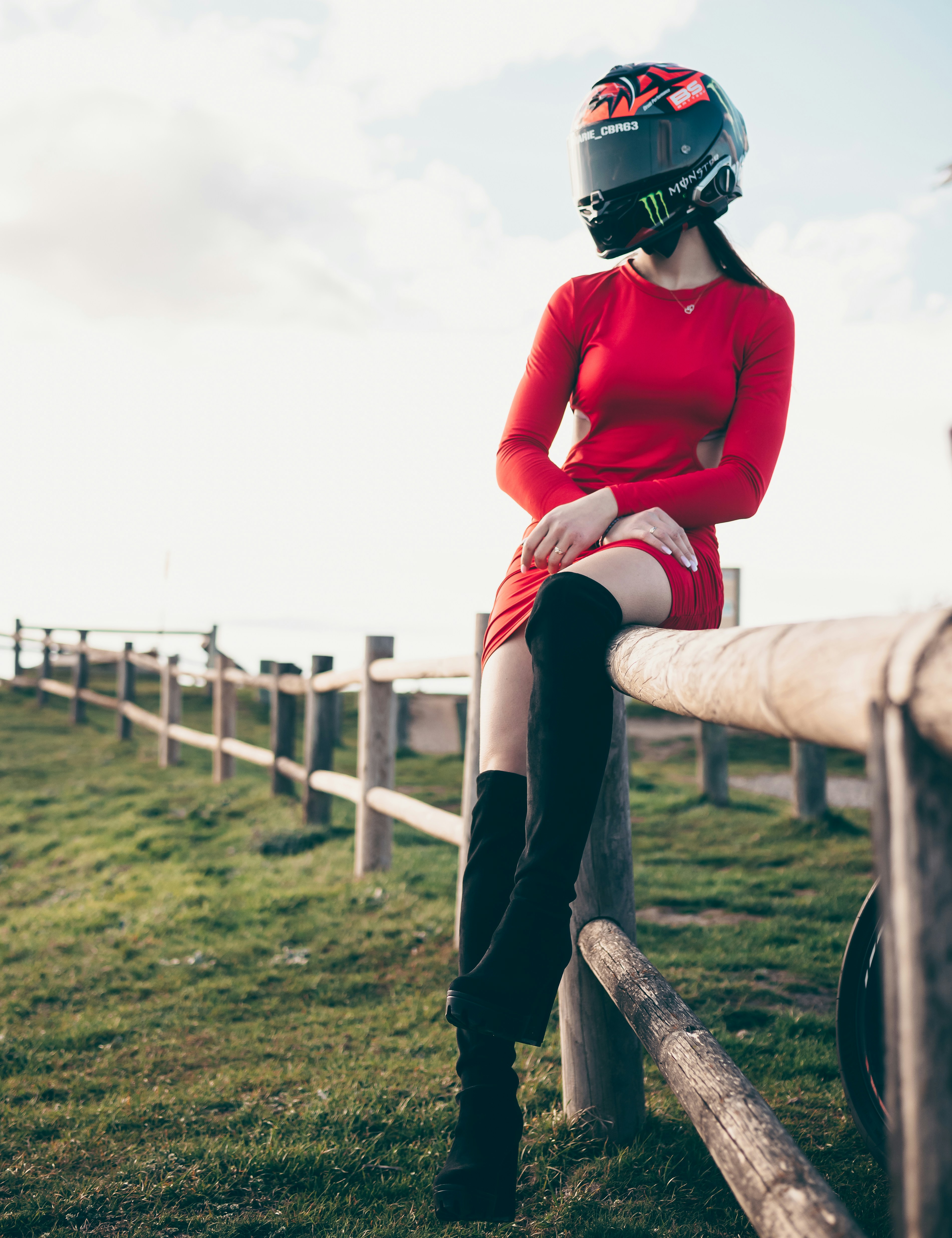 a woman in a red dress sitting on a fence