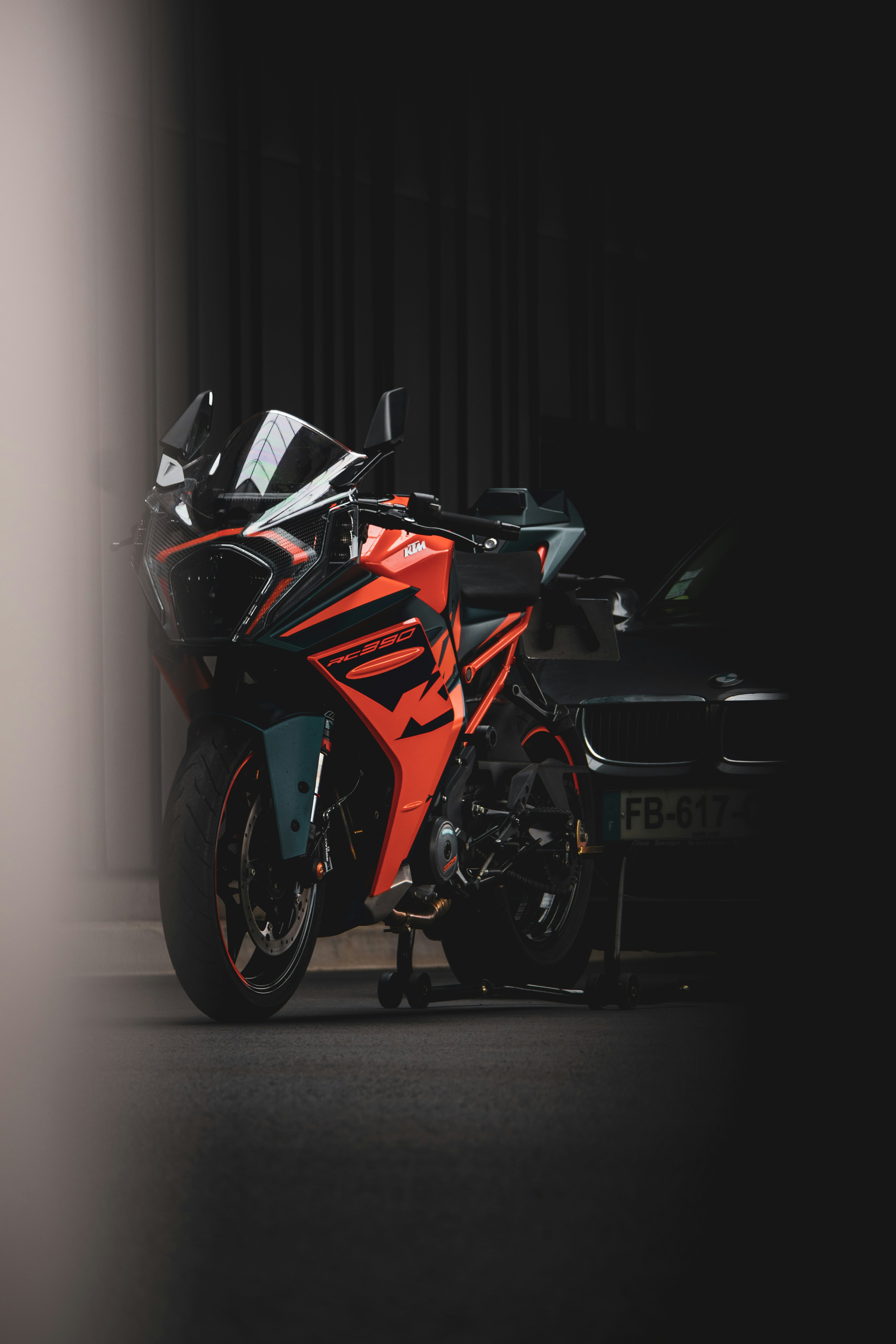 a red and black motorcycle parked next to a black car