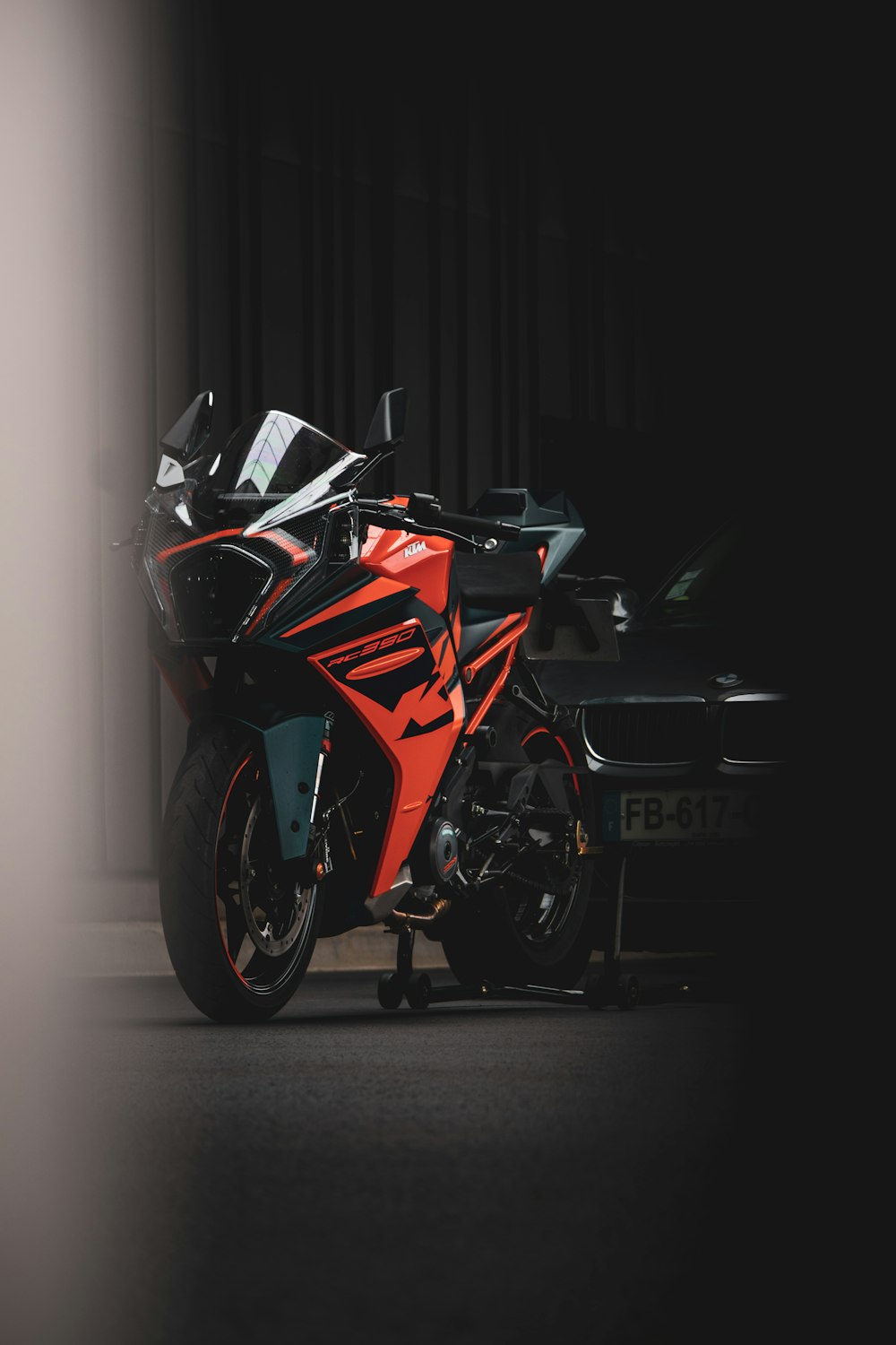 a red and black motorcycle parked next to a black car