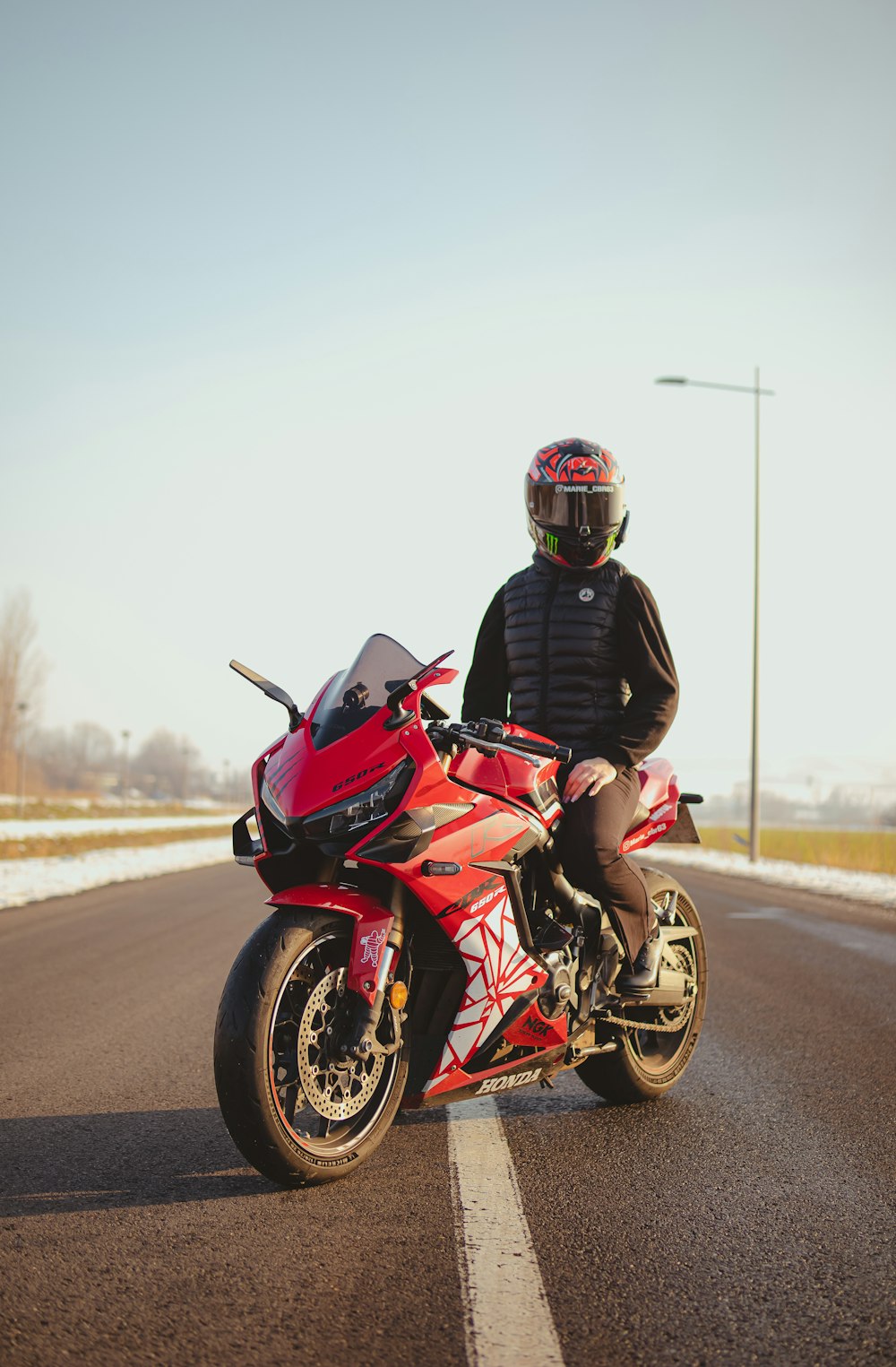 a man riding a red motorcycle down a street