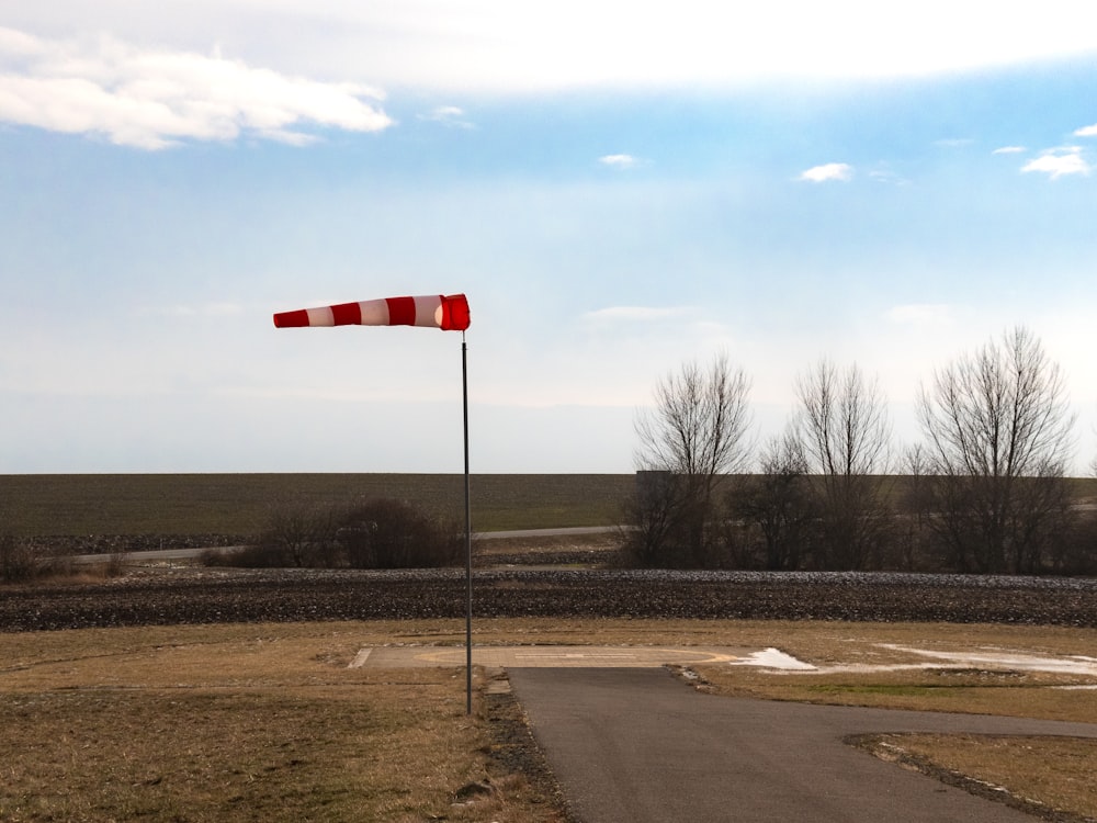a red and white flag on a pole next to a road