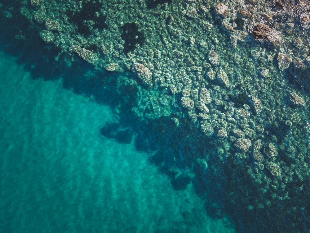 an aerial view of the ocean with rocks and water