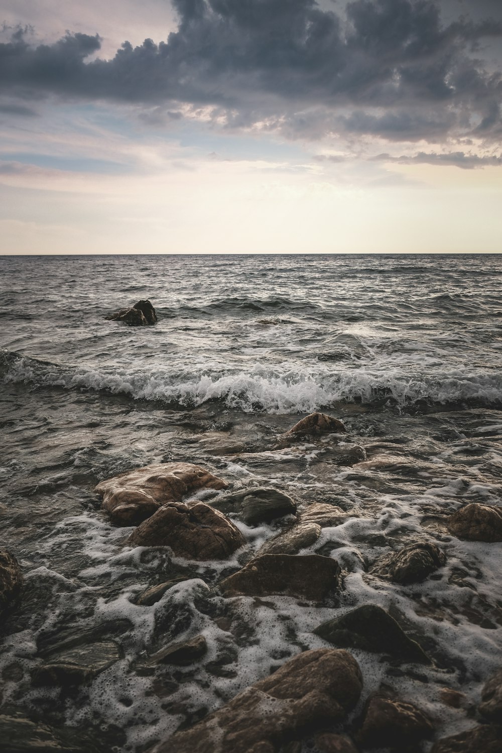 a body of water surrounded by rocks under a cloudy sky