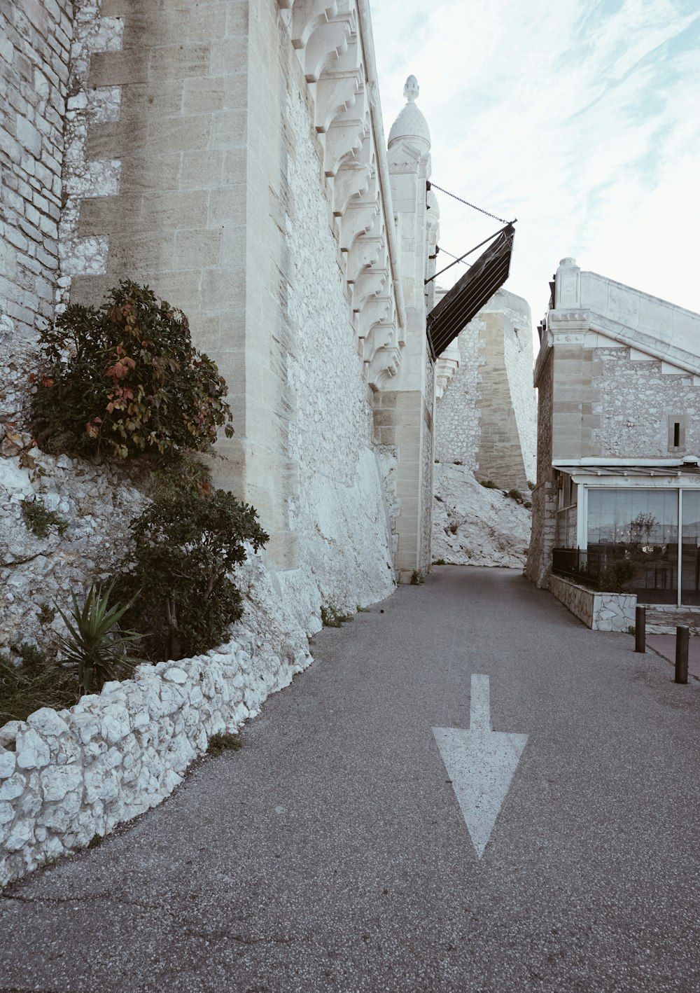 a white arrow on a road next to a building