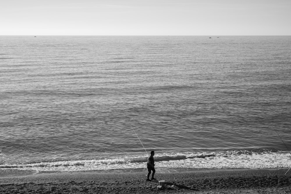 a man standing on top of a beach next to the ocean