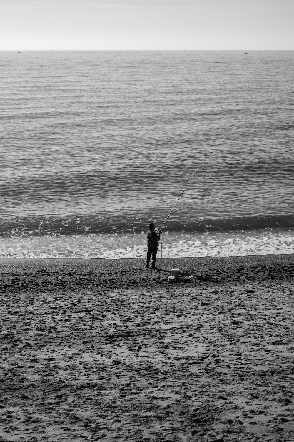 Ein Mann steht auf einem Sandstrand neben dem Meer