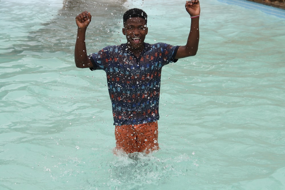 a man standing in a pool with his arms in the air