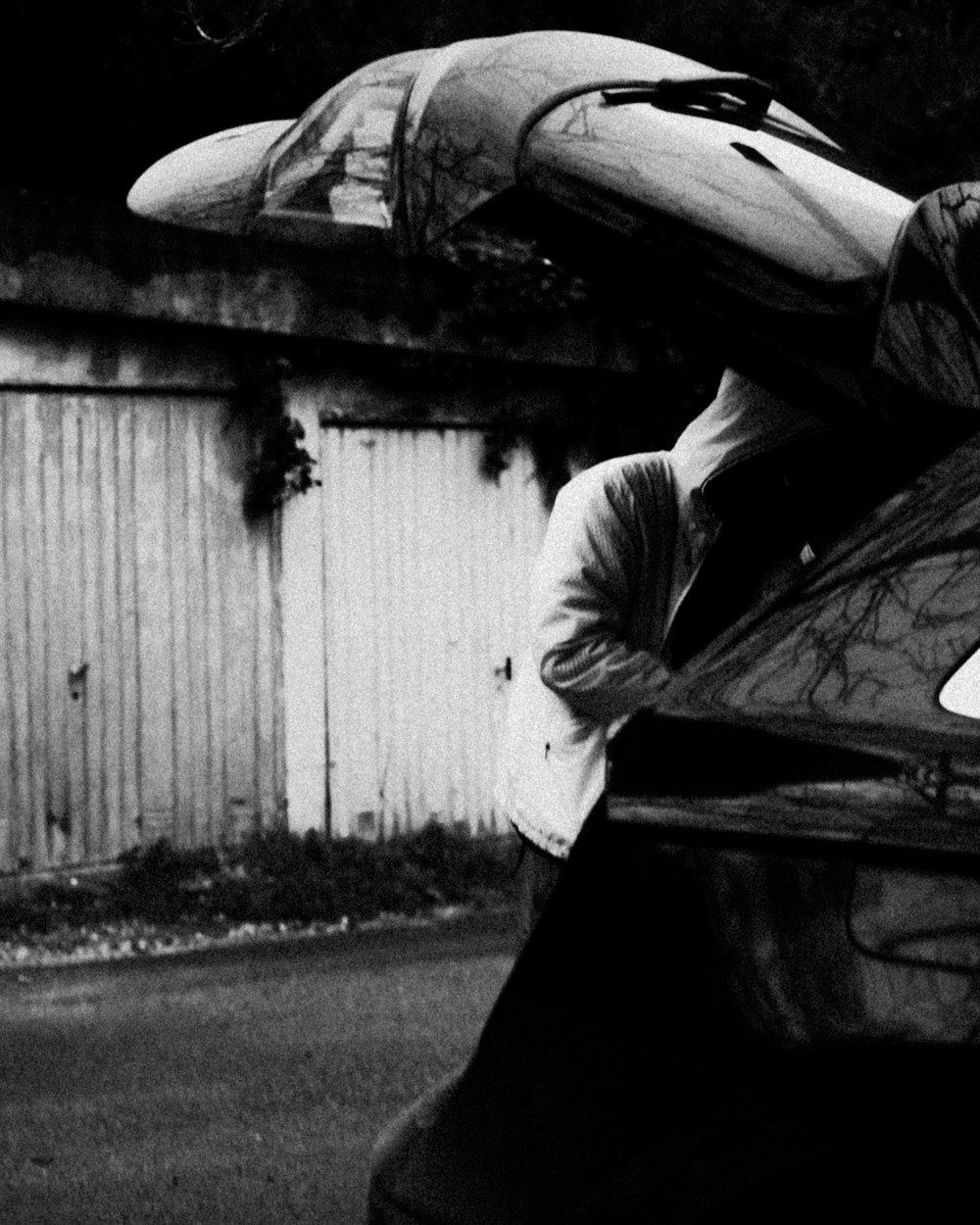 a black and white photo of a man carrying a surfboard