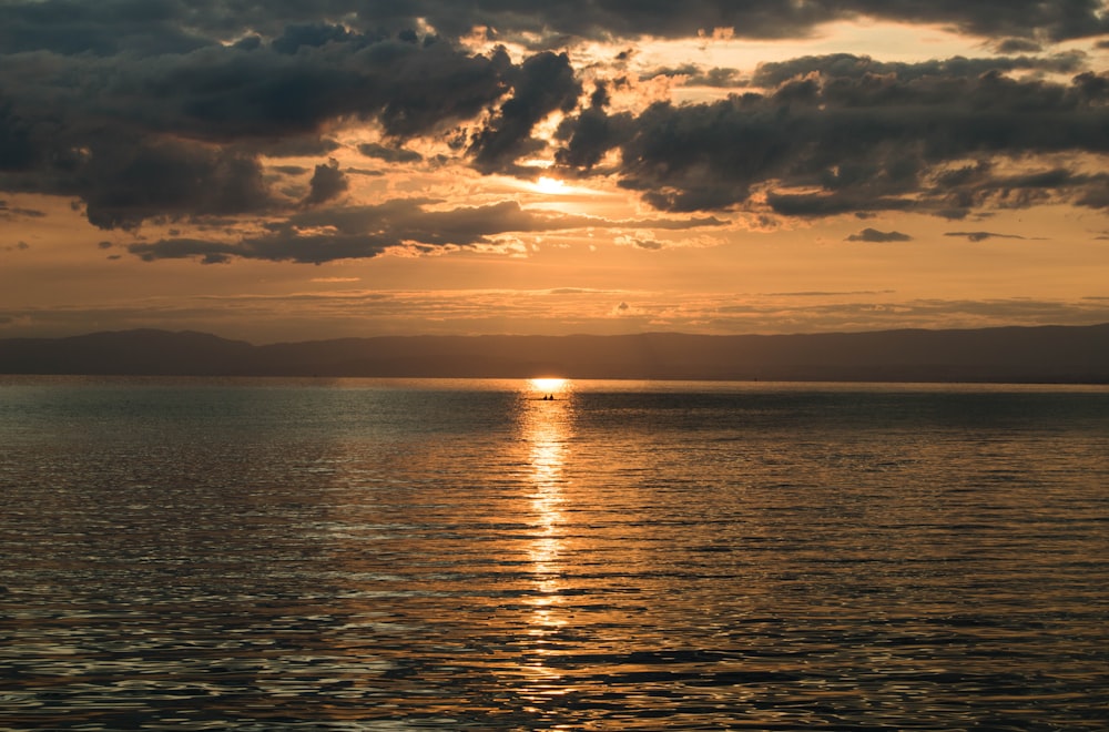 a large body of water with a sunset in the background