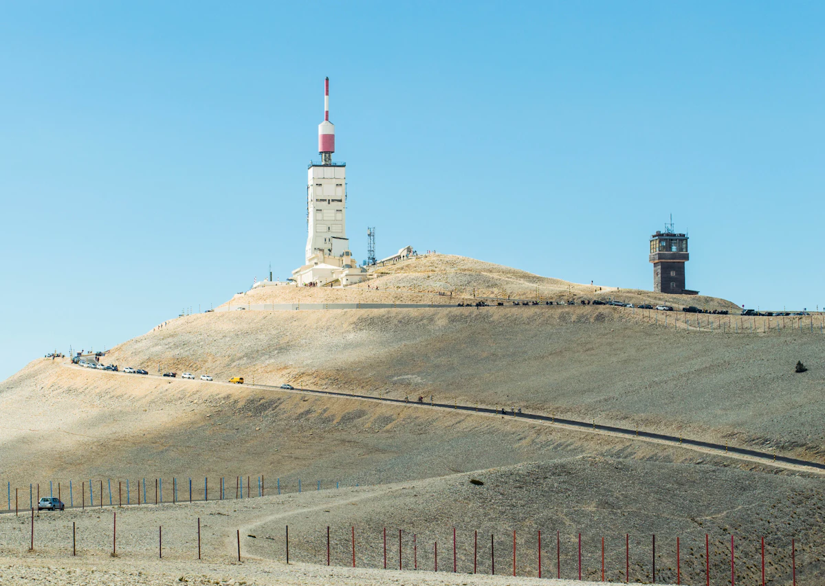 The bare summit of Mont Ventoux, with its radio mast, a stone tower and the road across the top