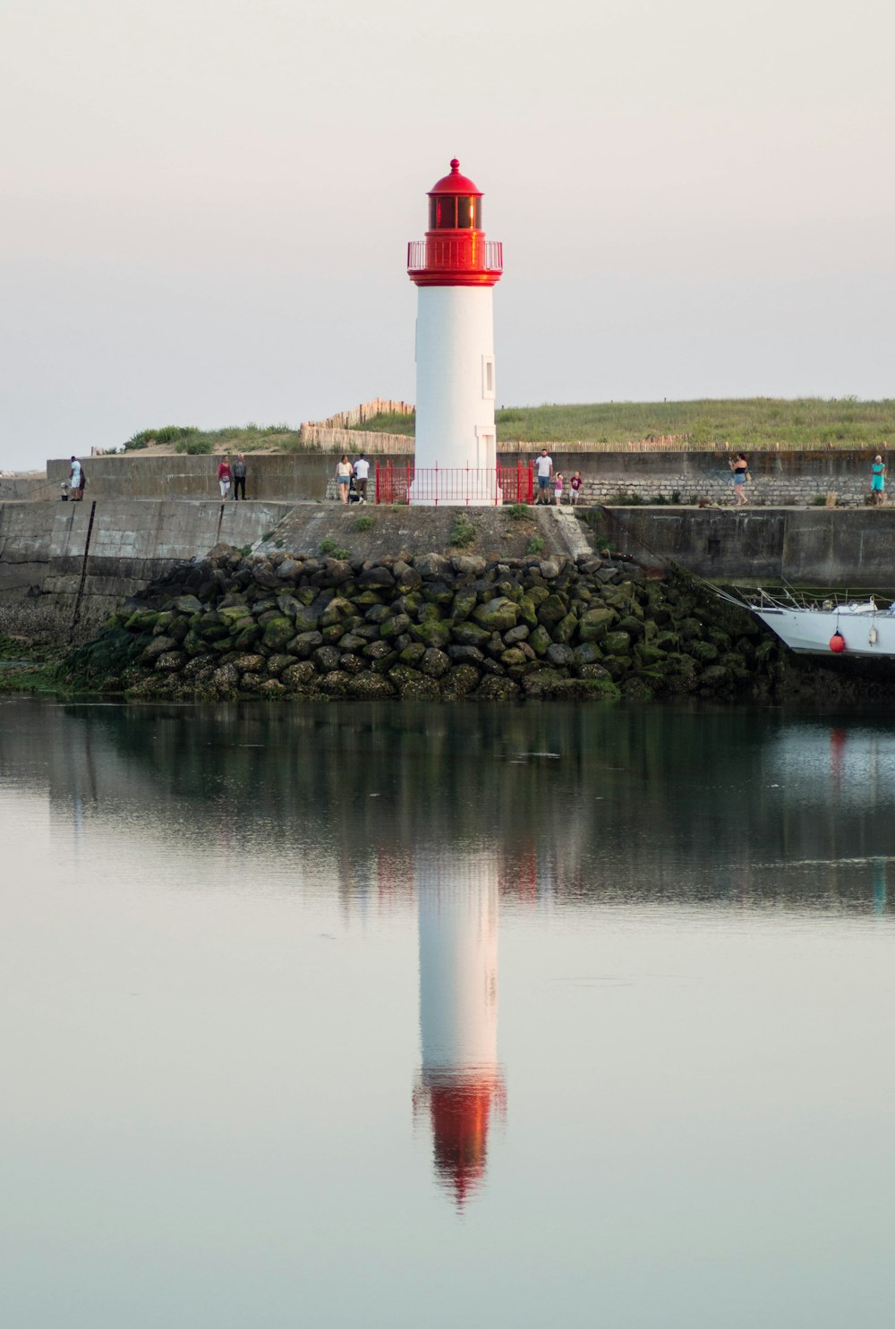 a red and white light house sitting on top of a body of water