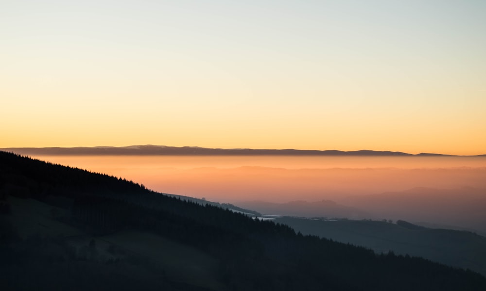 霧を伴った山々に沈む夕日