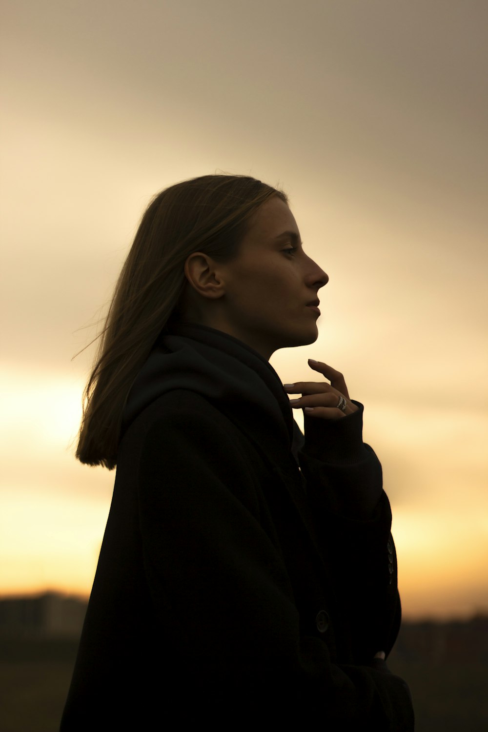 a woman standing in front of a sunset