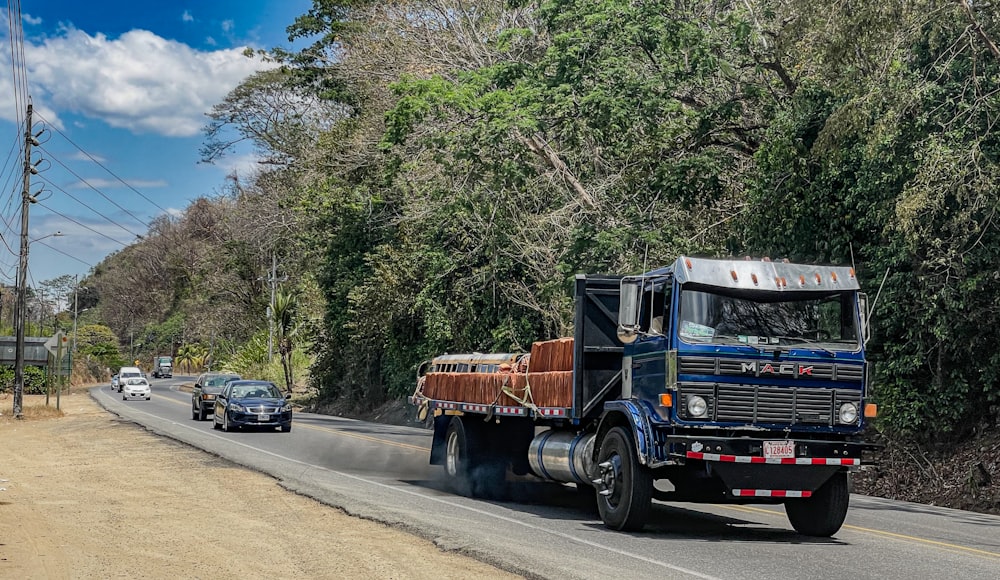 a truck driving down a road next to a forest