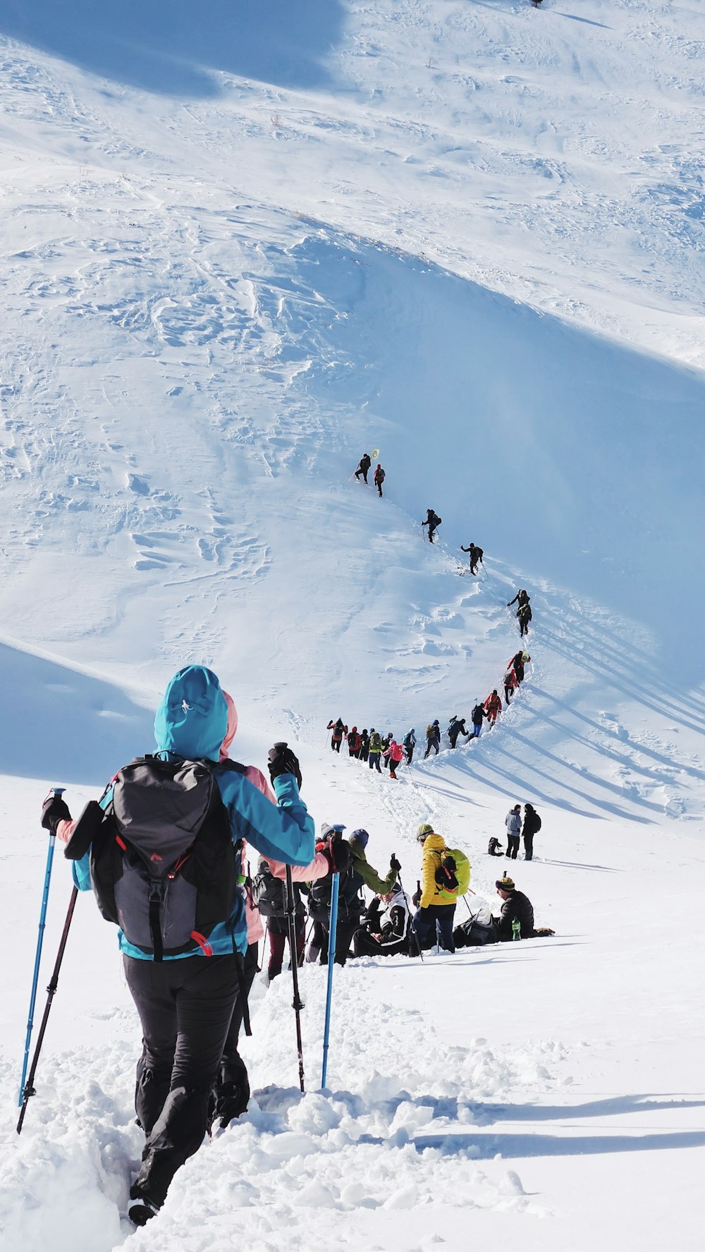 a group of people walking up the side of a snow covered slope