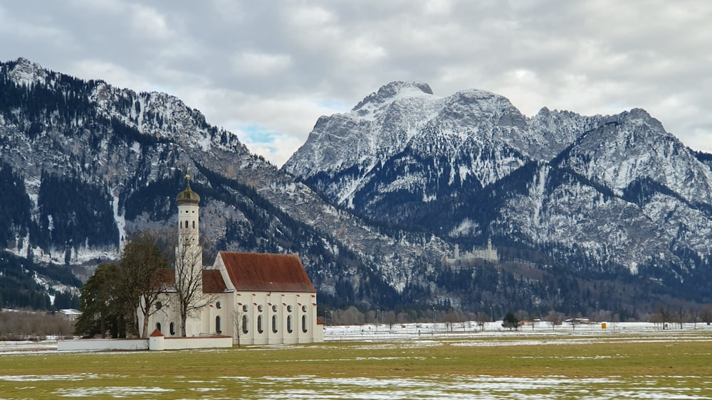 a church in a field with mountains in the background