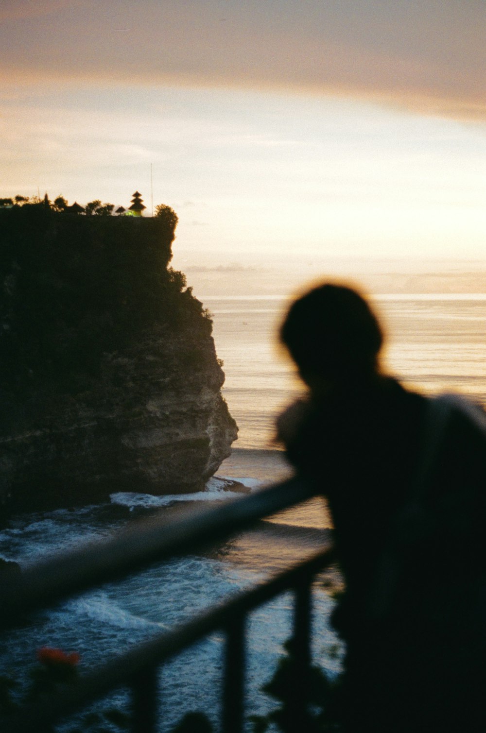 a man standing on top of a balcony next to the ocean