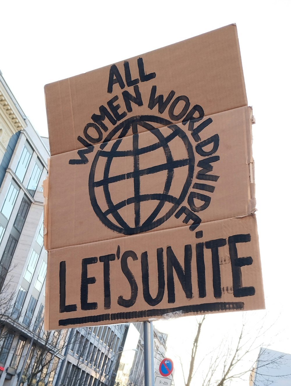 a cardboard sign that says, all women work for the world, let's