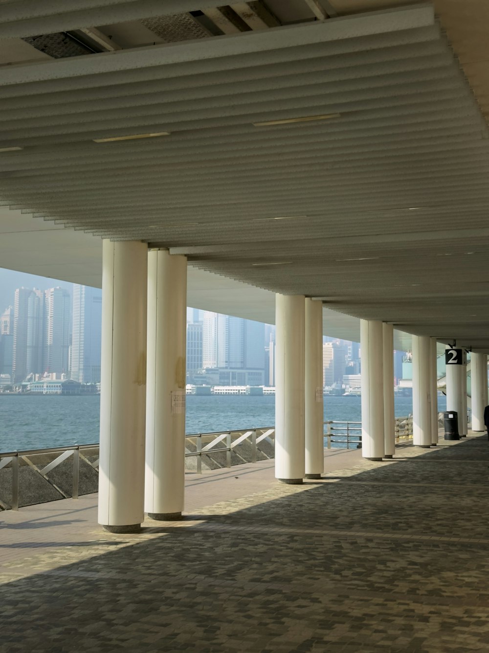 a row of white pillars next to a body of water